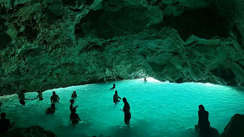 Participantes del tour en barco disfrutando de las brillantes aguas turquesas dentro de la Cueva Azul en Vlora