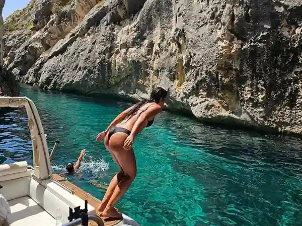 Mujer saltando a aguas cristalinas en el Cañón de los Contrabandistas, cerca de la península de Karaburun, Vlora