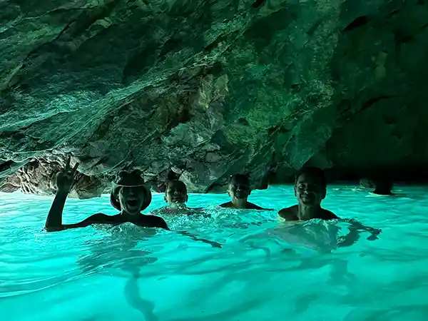 Grupo de turistas nadando en aguas turquesas brillantes dentro de la Cueva Azul