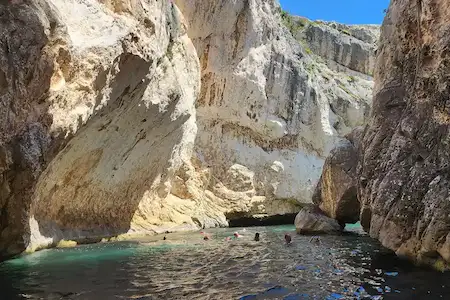 Visitantes nadando dentro del Cañón de los Contrabandistas, un espectacular pasaje costero rocoso durante un tour en barco a la Bahía de Grama, Vlora, Albania.