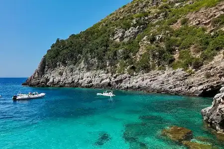 Lanchas rápidas fondeadas en las aguas turquesas y cristalinas de la bahía de Dafina, junto a la rocosa península de Karaburun, cerca de la Bahía de Grama, Vlora, Albania.
